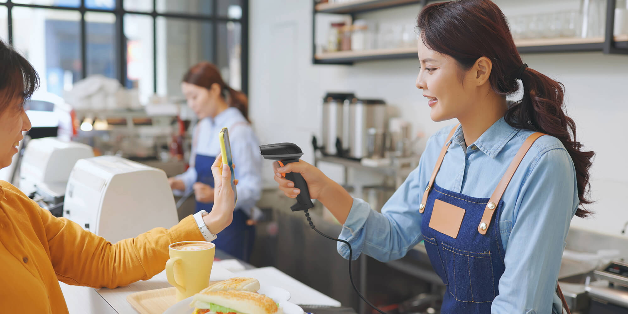 Store clerk using a handheld barcode scanner to scan a barcode from a customer’s phone